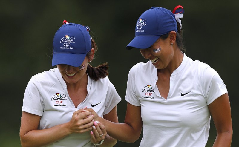 University of Arkansas golfers Kaylee Benton (left) and Dylan Kim, playing for the United States, celebrate after winning a hole during the third round of the Arnold Palmer Cup on Saturday at the Alotian Club in Roland. For more photos, see arkansasonline.com/609palmer/