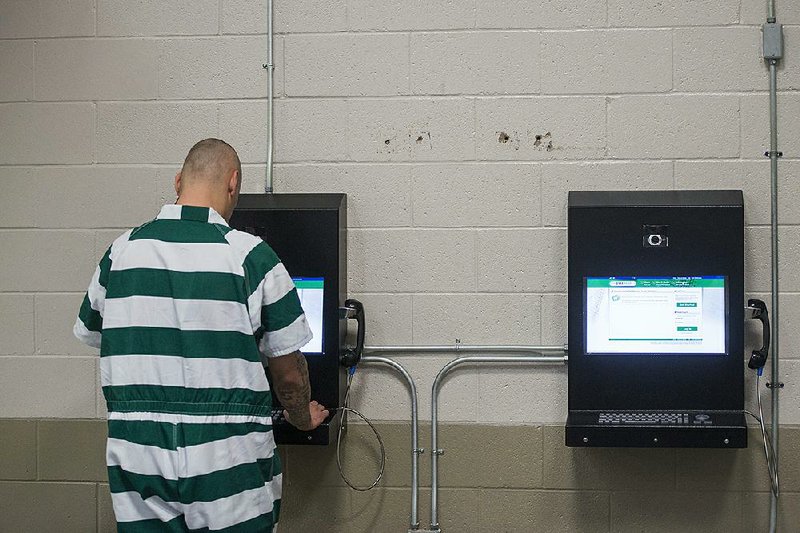 An inmate uses one of the email kiosks at the Benton County jail in Bentonville. 