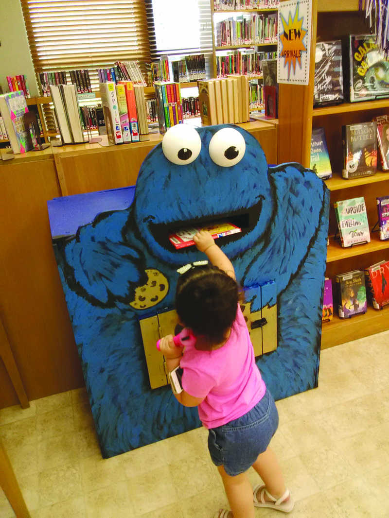 Cookie Monster: Amira, age 2, excitedly drops a book in the new Cookie Monster themed book return in the Children's room at Barton Library. The book drop was created by Bob Stephenson and painted by Mike Means, along with other volunteers at The South Arkansas Arts Center.
