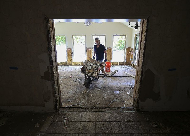 Ryan Bennett on Monday afternoon tears out Sheetrock from his grandmother’s house on Willow Beach Road in North Little Rock after floodwaters got inside last week. 