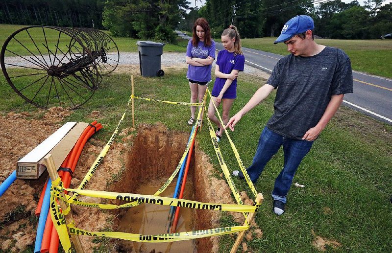 Abigail (from left), Leah and Riley Shaw stand around a fiber-optic line that is expected to provide Internet service to the family’s home on the outskirts of Starkville, Miss. 