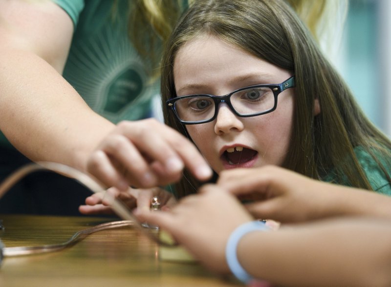 Addison Garrett reacts Monday as a fellow student uses a lighting device to demonstrate kinetic and potential energy during a STEM summer camp at Grimes Elementary School in Rogers. Participants of the camp learned the difference between kinetic and potential energy and applied their knowledge through a variety of creative activities. NWA Democrat-Gazette/CHARLIE KAIJO