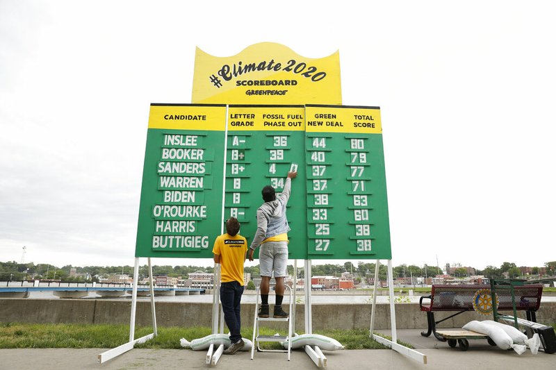 Simran McKenna, left, and Tracye Redd with Green Peace erect a climate 2020 scoreboard before a town hall meeting attended by Democratic presidential candidate and former Vice President Joe Biden, Tuesday, June 11, 2019, in Ottumwa, Iowa. (AP Photo/Matthew Putney)