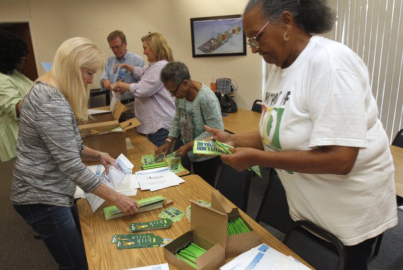 Keeping Clean: Keep El Dorado Beautiful members Diane Hammond, left, along with Janis Van Hook, right, and other volunteers, work to fill gift bags with trinkets at Clean Harbors on May 14. The bags consist of coloring book, stickers and other items for third and fourth graders to help reinforce the idea of keeping their environment clean. story.lead_photo.caption