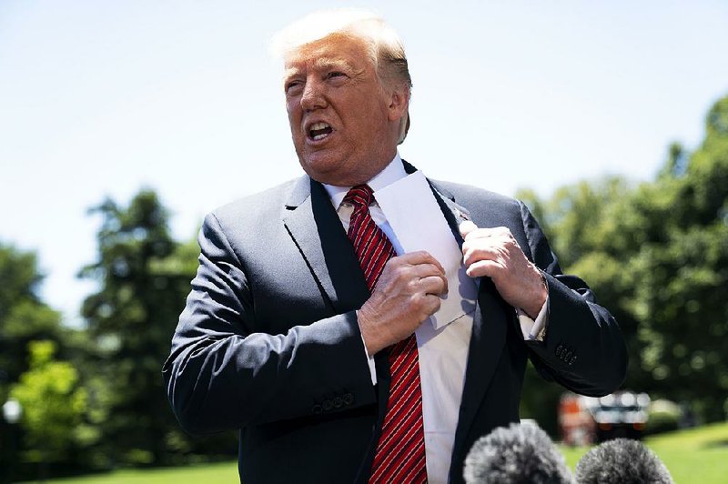 President Donald Trump puts away a page from what he said was a lengthy secret agreement with Mexico during a session with reporters Tuesday outside the White House. 