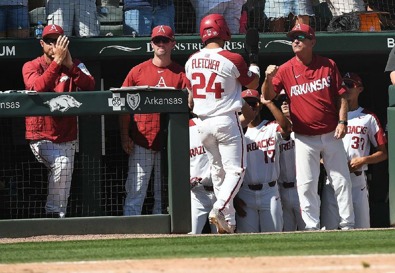 Arkansas Coach Dave Van Horn (right) congratulates Dominic Fletcher after he scored during the Razorbacks’ 14-1 victory over Ole Miss in Monday’s final game of the NCAA Fayetteville Super Regional at Baum-Walker Stadium. Arkansas opens play in the College World Series at Omaha, Neb., on Saturday against Florida State. 