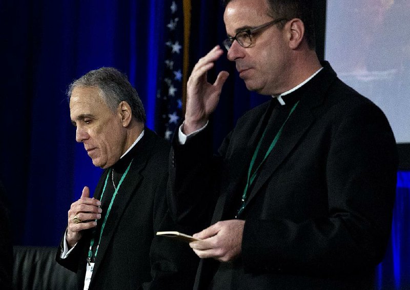 Cardinal Daniel DiNardo (left), president of the Roman Catholic bishops’ conference, joins the Rev. J. Brian Bransfield and others in a morning prayer Tuesday in Baltimore before the start of their meeting. 