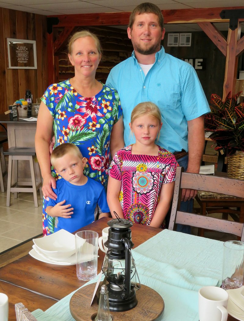 Westside Eagle Observer/RANDY MOLL Rustin and Gwyn Unruh, with the help of children Collin and Maddison, cut the ribbon on their new furniture store in Gentry, Flint Creek Amish Furniture, on Thursday (June 6, 2019). The new store features hand-crafted all wood furniture.