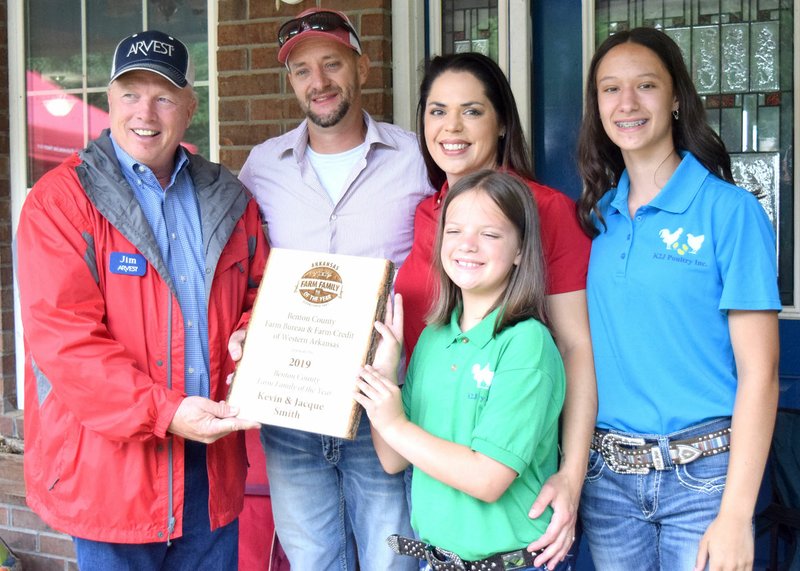 Westside Eagle Observer/MIKE ECKELS Jim Singleton, chairman of the Benton County Farm Family Selection Committee, presents the 2019 Benton County Farm Family of the Year award to Kevin Smith (second from left) and his family at their home in Decatur June 7. Joining Smith for the presentation was his wife Jacque and daughters Kylie (front) and Jacey.