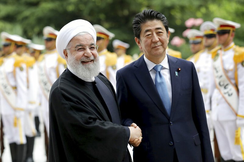 Japanese Prime Minister Shinzo Abe, right, shakes hands for the cameras with Iranian President Hassan Rouhani, during the official arrival ceremony, at the Saadabad Palace in Tehran, Iran, Wednesday, June 12, 2019. (AP Photo/Ebrahim Noroozi) story.lead_photo.caption