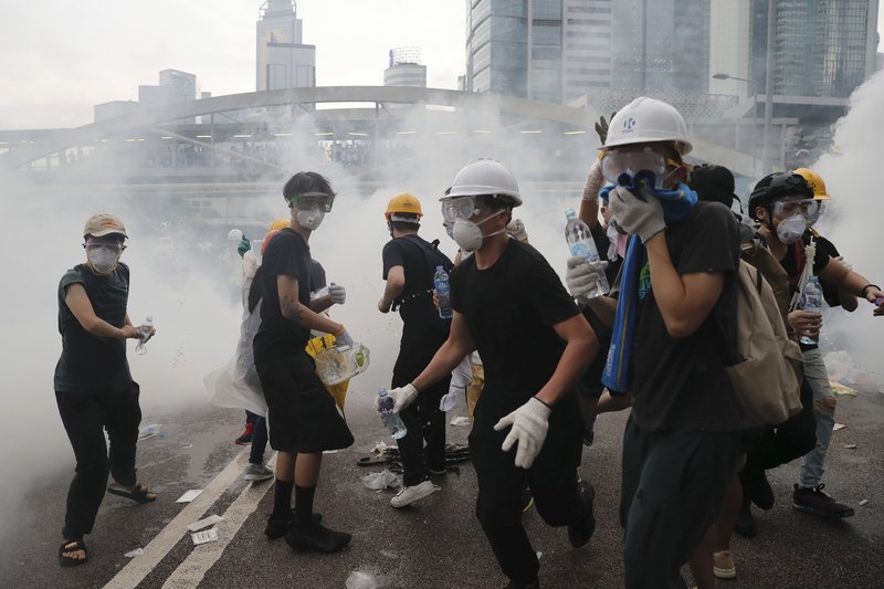 Demonstrators react to a cloud of tear gas near the Legislative Council in Hong Kong, Wednesday, June 12, 2019. Hong Kong police fired tear gas and high-pressure water hoses against protesters who had massed outside government headquarters Wednesday in opposition to a proposed extradition bill that has become a lightning rod for concerns over greater Chinese control and erosion of civil liberties in the semiautonomous territory. (AP Photo/Kin Cheung) story.lead_photo.caption
