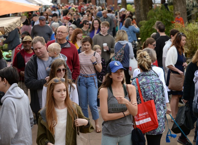 A large crowd walks along the sidewalk Saturday, April 6, 2019, during the Fayetteville Farmers' Market on the city's downtown square. The market will be open three days a week on the square from 7 a.m. to 1 p.m. Tuesdays and Thursdays through Oct. 30 and 7 a.m. to 2 p.m. Saturdays through Nov. 17. Vendors provide locally grown flowers, produce, meats, eggs, baked goods, plants and arts and crafts.