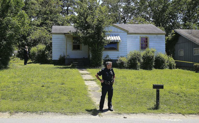 A Little Rock Police officer stands in front of a house at 4601 W. 16th St. where detectives were investigating a triple homicide Thursday afternoon.