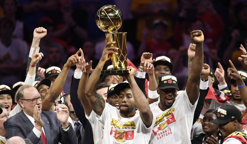 Toronto Raptors forward Kawhi Leonard, centers, holds the Larry O'Brien NBA Championship Trophy after the Raptors defeated the Golden State Warriors 114-110 in Game 6 of basketball s NBA Finals, Thursday, June 13, 2019, in Oakland, Calif. 