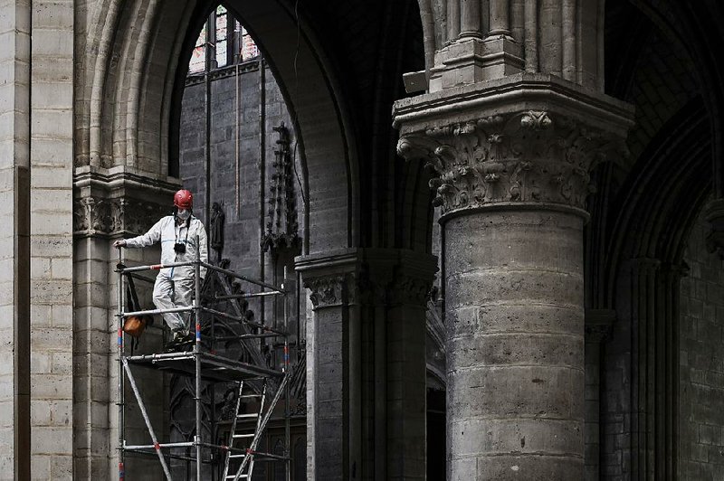 A worker stands on scaffolding last month as reconstruction started at Notre Dame Cathedral in Paris, which sustained extensive damage in an April 15 fire. 