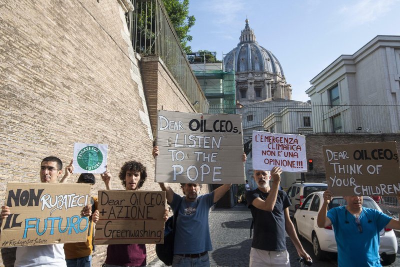 Activists hold up signs outside the Vatican as Pope Francis meets with oil executives, Friday, June 14, 2019. The meeting marked the second year that Francis has invited oil and financial sector executives to the Vatican to impress upon them his concern that preserving God&#x2019;s creation is one of the fundamental challenges facing humankind today. Signs in Italian read &quot;Don't steal our future&quot;, left, and &quot;Climate emergency is not an opinion!&quot;, second from right. (Claudio Peri/ANSA via AP)