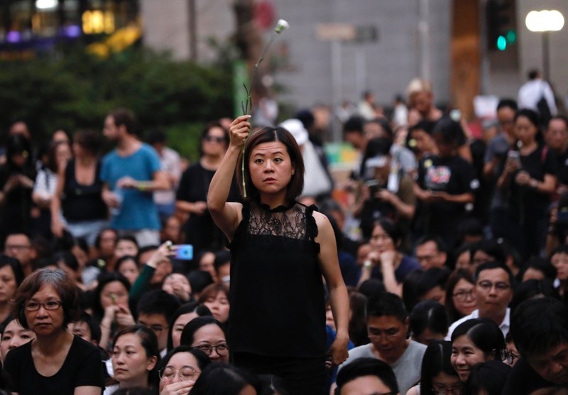 A woman holds a flower as she joins hundreds of mothers protesting against the amendments to the extradition law after Wednesday's violent protest in Hong Kong on Friday, June 14, 2019. Calm appeared to have returned to Hong Kong after days of protests by students and human rights activists opposed to a bill that would allow suspects to be tried in mainland Chinese courts. (AP Photo/Vincent Yu)