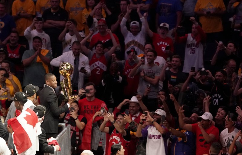 This Thursday, June 13, 2019, photo shows Toronto Raptors general manager Masai Ujiri holding the championship trophy after the Raptors defeated the Golden State Warriors in Game 6 of basketball's NBA Finals in Oakland, Calif. Authorities say they are investigating whether Toronto Raptors president Masai Ujiri pushed and hit a sheriff's deputy in the face as he tried to get on the court after his team won the NBA title in Oakland. (AP Photo/Tony Avelar)