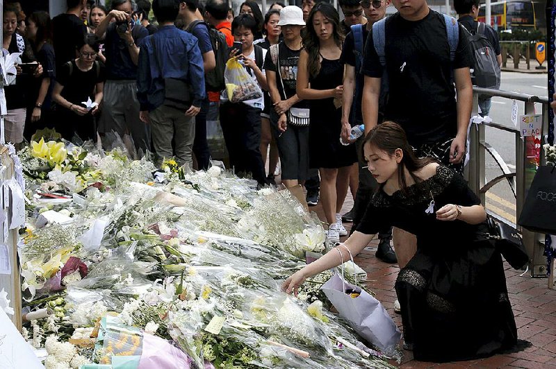 Mourners stop by a makeshift memorial Sunday to lay flowers and pray for a man who fell to his death Saturday after hanging a protest banner against an extradition bill in Hong Kong.