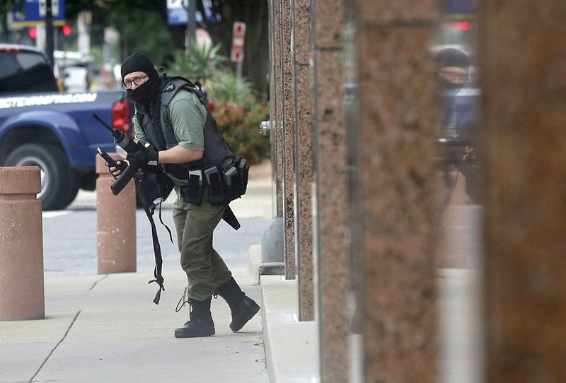 An armed shooter stands near the Earle Cabell Federal Building Monday, June 17, 2019, in downtown Dallas. The shooter was hit and injured in an exchange of gunfire with federal officers outside the courthouse. (Tom Fox/The Dallas Morning News) MANDATORY CREDIT, NO SALES, MAGS OUT, TV OUT, INTERNET USE BY AP MEMBERS ONLY