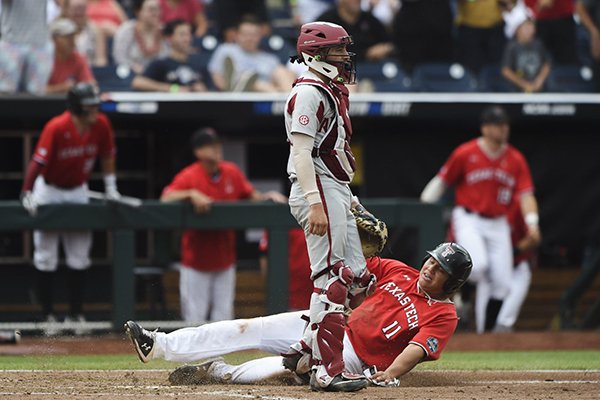 Texas Tech first baseman Cameron Warren slides into home plate as Arkansas catcher Casey Opitz stands during a College World Series game Monday, June 17, 2019, at TD Ameritrade Park in Omaha, Neb.