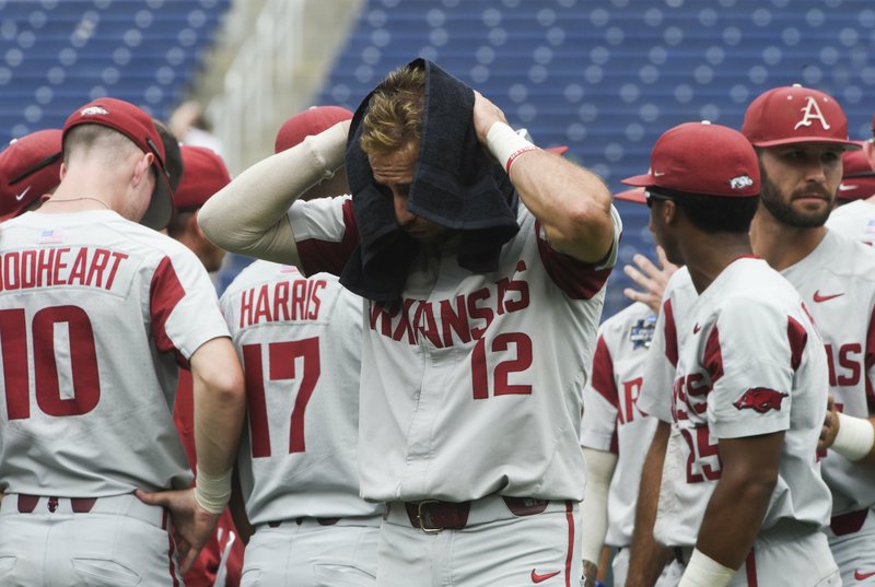 NWA Democrat-Gazette/Charlie Kaijo DEJECTED HOGS: Arkansas Razorbacks catcher Casey Opitz (12) and teammates react after a 5-4 loss against Texas Tech during Monday's College World Series elimination game at the TD Ameritrade Park in Omaha, Neb.