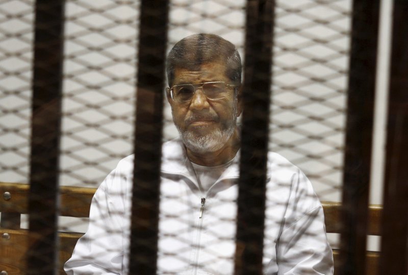 FILE - In this May 8, 2014 file photo, Egypt's ousted Islamist President Mohammed Morsi sits in a defendant cage in the Police Academy courthouse in Cairo, Egypt. On Monday June 17, 2019, Egypt's state TV said the country's ousted President Mohammed Morsi, 67, collapsed during a court session and died. It said it occurred while he was attending a court trial on espionage charges. Morsi, who hailed from Egypt's largest Islamist group, the now outlawed Muslim Brotherhood, was elected president in 2012 in the country's first free elections following the ouster the year before of longtime leader Hosni Mubarak. (AP Photo/Tarek el-Gabbas, File)