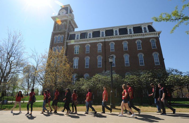 Kassandra Salazar (left) speaks Tuesday, April 5, 2016, to a group of 11th-grade students from Heritage High School in Rogers as they walk past Old Main while on a tour of the university campus in Fayetteville.