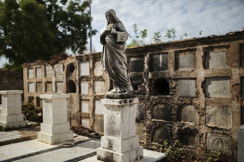 A statue stands beside empty pedestals in front of desecrated vaults in El Cuadrado cemetery in Maracaibo, Venezuela, in this photo taken May 16. A once-thriving oil industry has given way to desperation and exhaustion. 