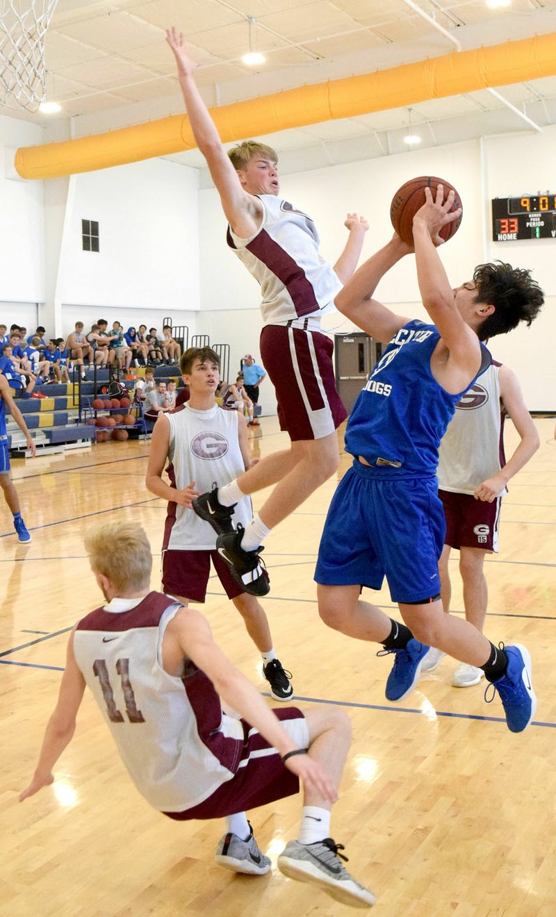 Westside Eagle Observer/MIKE ECKELS Surrounded by a host of Pioneer defenders, Decatur's Kevin Garcia (right) tries for a jumper during the Decatur-Gentry scrimmage game in the new gym at Decatur Middle School June 13. The Bulldogs claimed the victory over the Pioneers during day three of the Decatur summer league scrimmages.