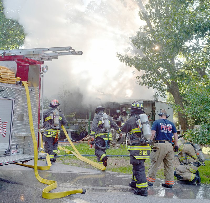 Keith Bryant/The Weekly Vista Bella Vista firefighters prepare to enter a burning house on Pine Street last Wednesday afternoon. Battalion Chief Ronnie Crupper said that there were no casualties but the structure was a total loss. The next house to the south suffered heat damage to its siding, but firefighters kept the flames from spreading, he said. "The guys did a good job protecting the surrounding exposures," Crupper said.