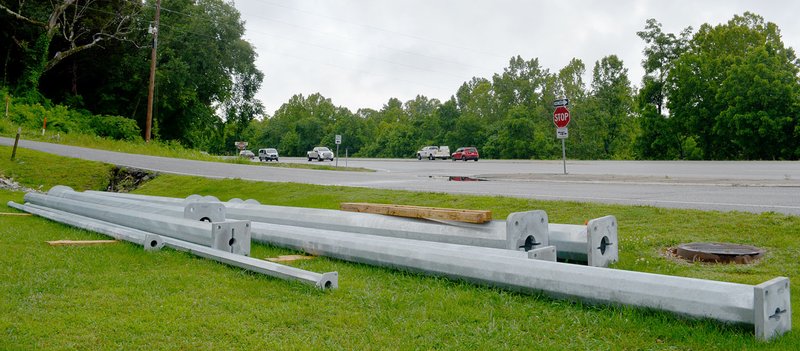 Keith Bryant/The Weekly Vista Poles sit ready to assemble a traffic signal at the intersection of U.S. Highway 71. Community Development Services director Doug Tapp said soil testing and drilling for the required concrete piers is set to begin soon, but the contractors need several rain-free days before they can begin. The project is expected to conclude in late August, he said, though it will be extended if the drilling process hits bedrock.