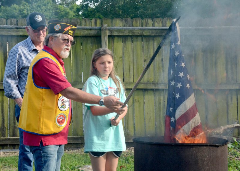 Janelle Jessen/Herald-Leader Jerry Langley (center), surgeon for Veterans of Foreign Wars Post 1674, helped Riley Kiker of Konawa, Okla., (right), retire an American Flag during the ceremony on Flag Day, Friday, June 14, as her grandpa (left), VFW member Bob Tyer, looked on.