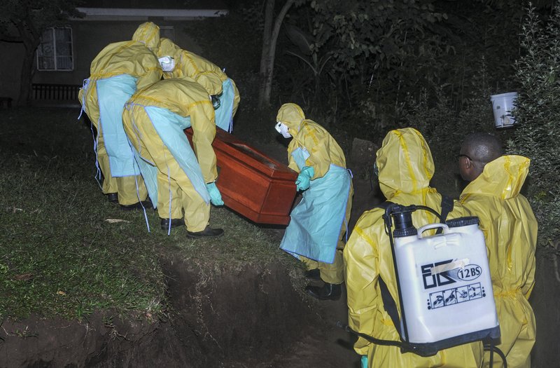 Workers wearing protective clothing bury Agnes Mbambu who died of Ebola, the 50-year-old grandmother of the 5-year-old boy who became Ebola's first cross-border victim, in the village of Karambi, near the border with Congo, in western Uganda Thursday, June 13, 2019. The two were part of a larger Congolese-Ugandan family who crossed to Congo when one of their elders there, a pastor, became sick with Ebola and they crossed back into Uganda on June 9 via a footpath not patrolled by border authorities. (AP Photo/Ronald Kabuubi)