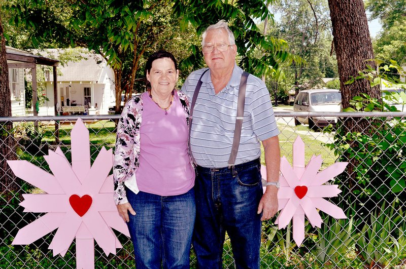 RACHEL DICKERSON/MCDONALD COUNTY PRESS After knowing each other for a lifetime, Patsy Ward (left) and Ed Malcolm of Pineville have found romance together following the loss of their spouses. They are pictured next to some of the larger examples of wooden flowers that Malcolm makes.