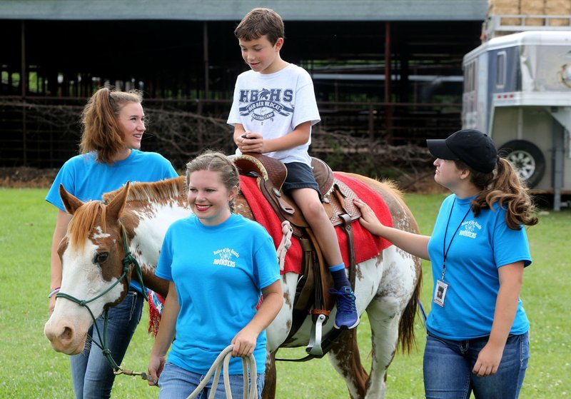 File Photo/DAVID GOTTSCHALK Carter Ebarb, 8, receives an escorted ride from Rodeo of the Ozarks Rounders Lauren Lemblee (from left), LeTausha Ahrents (cq) and Hanna Morgan at the 17th annual Super Cowboys Super Cowgirls event. The event is sponsored by the Rodeo of the Ozarks for children in the Family Support Program of Arkansas Support Network.