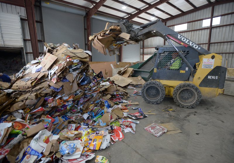 Mike Gillispie, a recycling worker with Boston Mountain Solid Waste District, uses a skid-steer loader Friday, Dec. 21, 2018, to feed cardboard into a bailing machine while sorting recyclables at the district's transfer station in Prairie Grove.