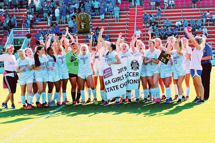 Madison Humbard, No. 3, hoists the Class 6A girls soccer state-championship trophy above her head as she and the rest of the Bryant Lady Hornets celebrate the team’s victory. Alyssa Fason, third from right, front, was named MVP. 
