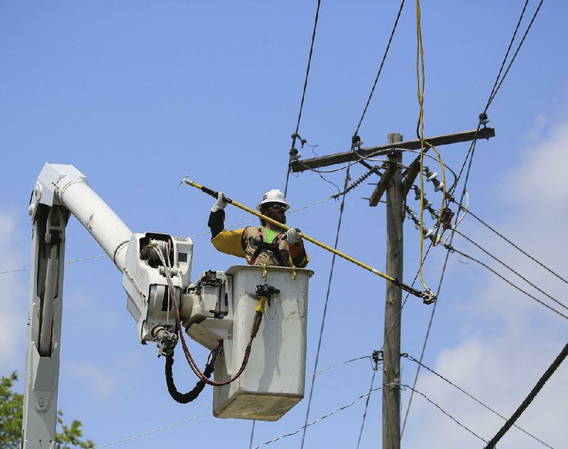 Jason Jones of VOLT Power sets grounds on power lines Friday before replacing damaged utility poles on Pinnacle Valley Road in western Pulaski County.