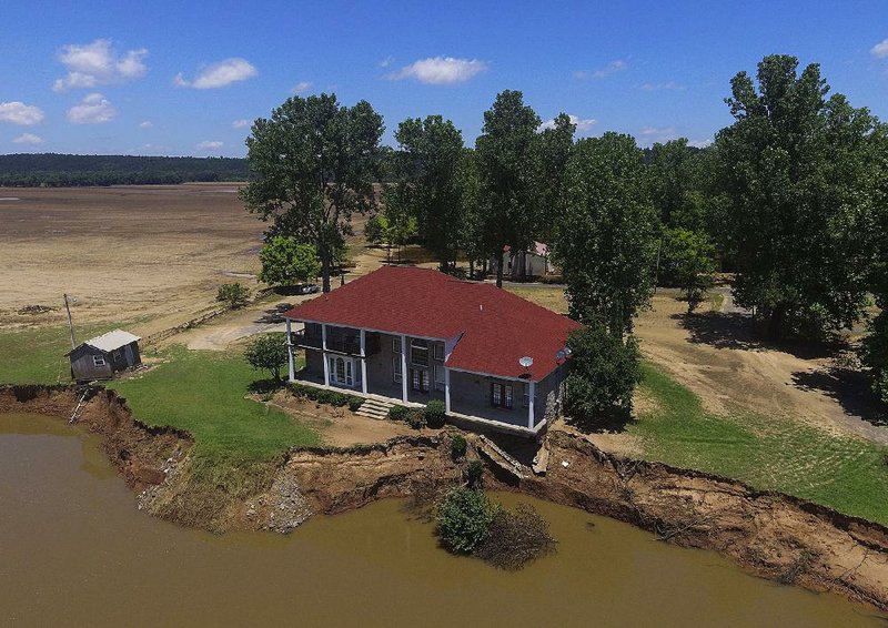 The corner of this house on Jones Lane in Mayflower sits precariously on the edge of the Arkansas River on Thursday after floodwaters washed away part of the bank.