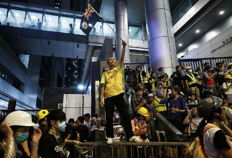 A protester waves a Hong Kong flag Friday outside police headquarters in the city. Protesters also shut down roads in the city center. 