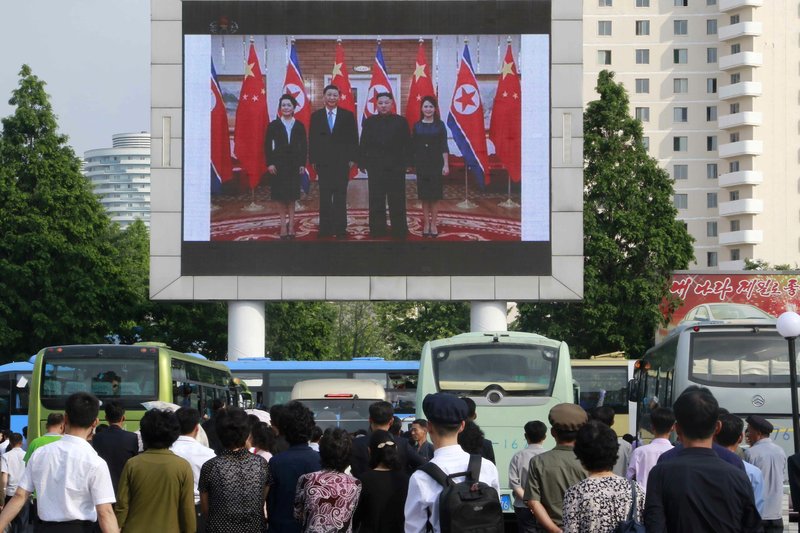 People watch a large screen showing an image of Chinese President Xi Jinping, second from left, posing with his wife Peng Liyuan, left, North Korean leader Kim Jong Un and his wife Ri Sol Ju, at Pyongyang Railway Station in Pyongyang, North Korea, Friday, June 21, 2019.  (AP Photo/Jon Chol Jin)