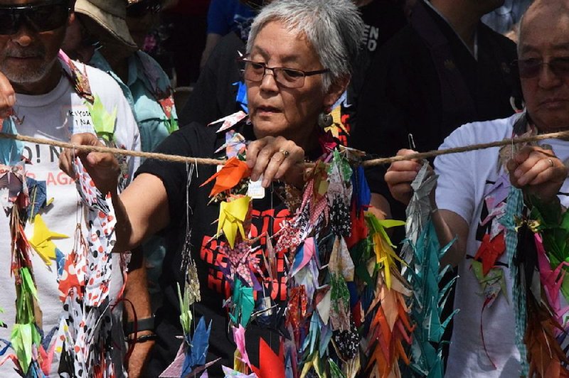 Satsuki Ina, 75, who was detained as a child in a U.S. internment camp for Japanese Americans, helps hang origami cranes Saturday at a park near Fort Sill, Okla., during a protest against a plan to house migrant children at the Army base.