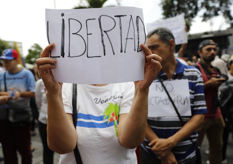 A woman holds up a sign that reads in Spanish "Freedom" during a protest against the government of Nicolas Maduro, outside of the United Nations Development Program office in Caracas, Venezuela, Friday, June 21, 2019. U.N.  (AP Photo/Ariana Cubillos)