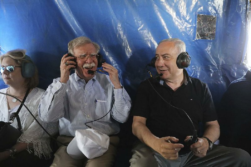 U.S. national security adviser John Bolton (left) grabs ear protectors Sunday during a flight in an Israeli military helicopter over the Jordan Valley with Israeli Prime Minister Benjamin Netanyahu. 