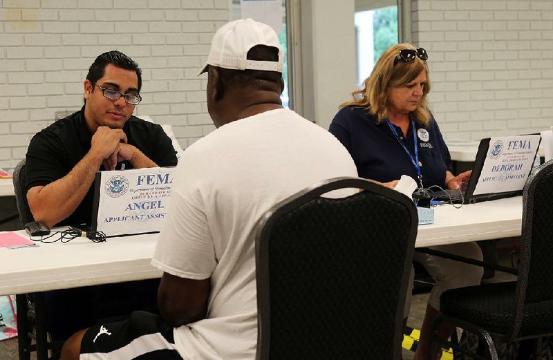 FEMA representative Angel Figueroa (left) assists a North Little Rock resident Sunday with disaster assistance paperwork at the FEMA offices now open in North Little Rock. 