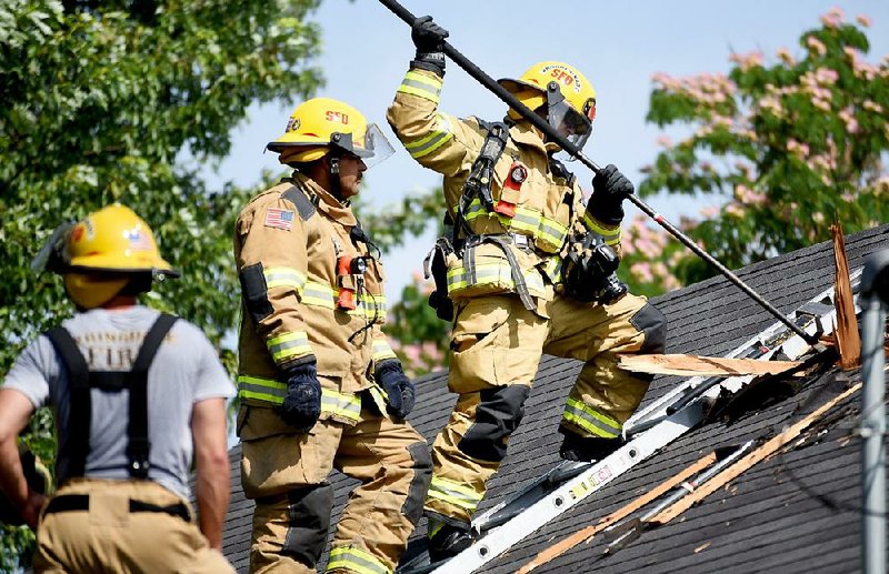 Ryan Anderson, (right), probationary firefighter with the city of Springdale, follows the instruction of driver operator Josh King during vertical ventilation training Friday at a house in Springdale. Several fire departments, including Springdale, will now hire firefighters as young as 18 because of a new law that lowered the minimum age from 21. 