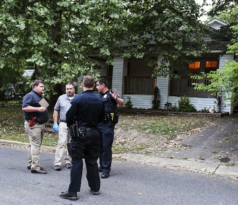 Detectives and patrolmen with the Hot Springs Police Department talk Saturday outside the scene of a fatal shooting at 315 North Patterson Street. 