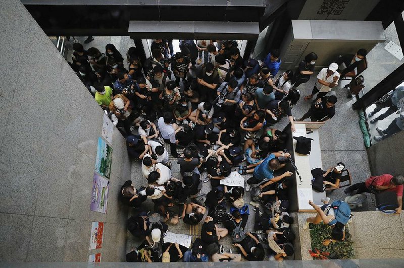 Protesters sit down to block the entrance to Hong Kong’s Inland Revenue Tower on Monday.