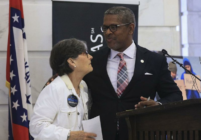 AT&T Arkansas President Ronnie Dedman presents Kathy Webb, executive director of the Arkansas Hunger Relief Alliance, with a check Monday during a news conference at the state Capitol to announce the Believe Arkansas initiative. 